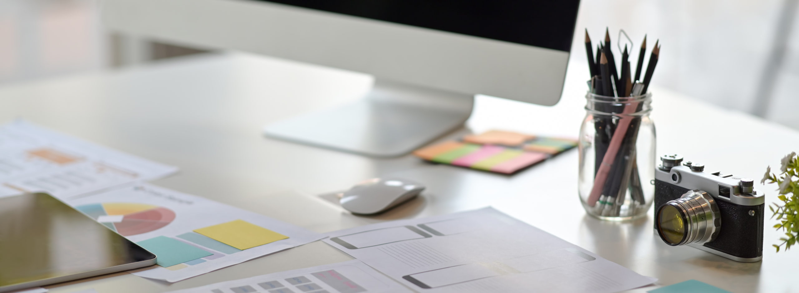 Cropped shot of UI developer workspace with computer, stationery and paperwork on white desk