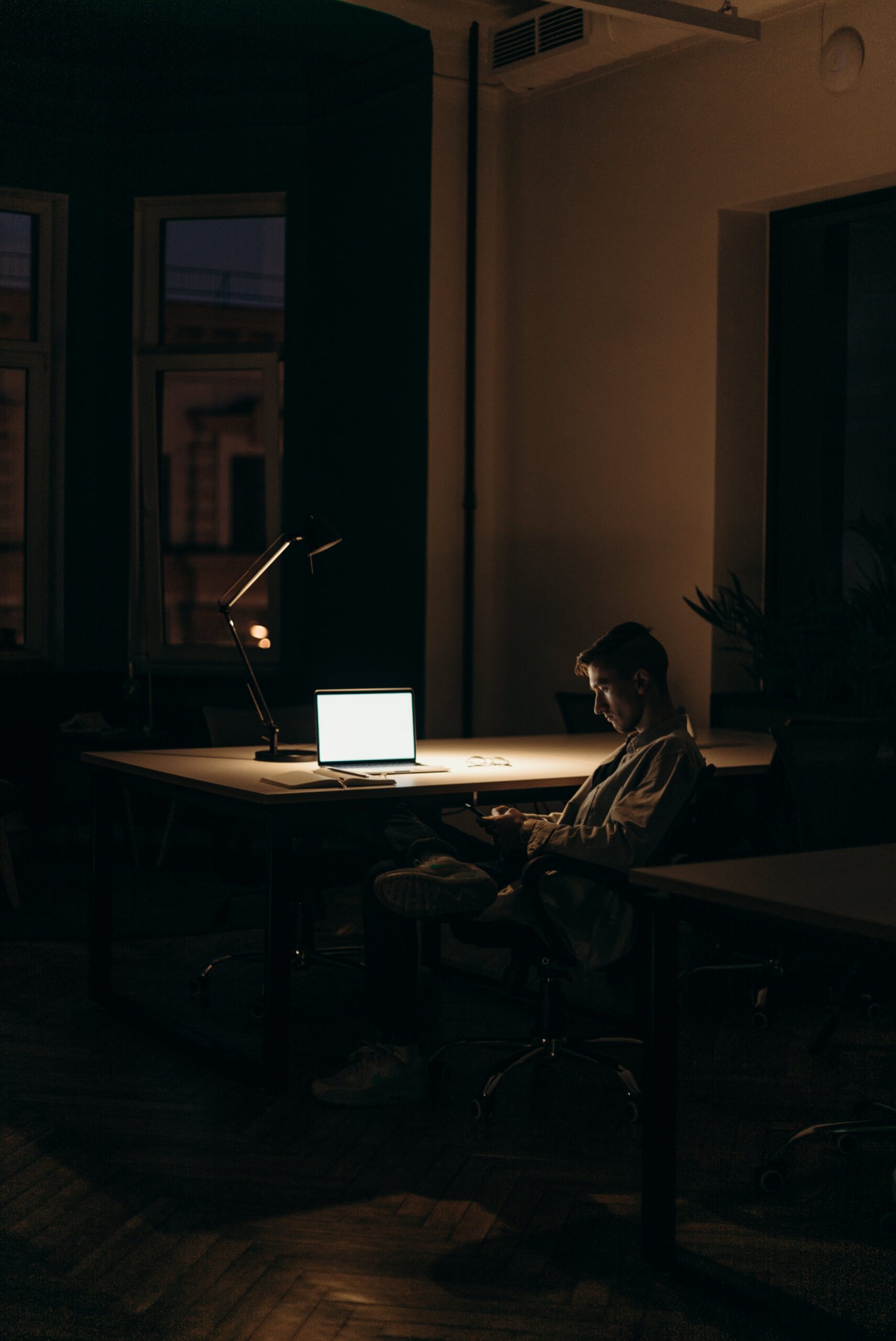 man in black and white stripe dress shirt sitting on a chair in front of macbook