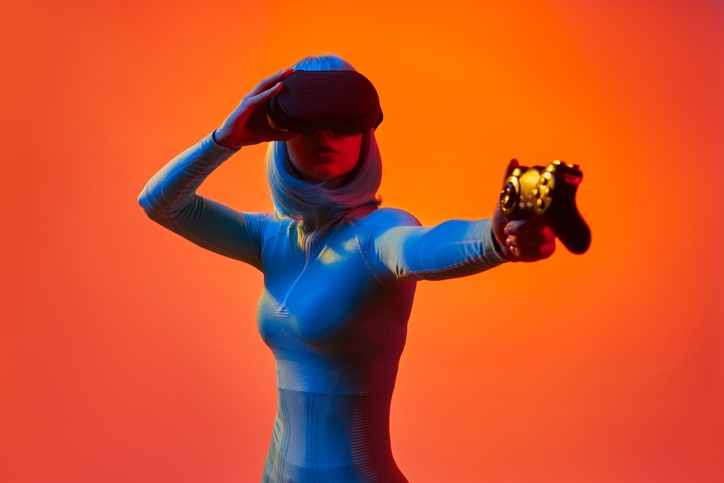 Woman in VR goggles holding gamepad like gun
