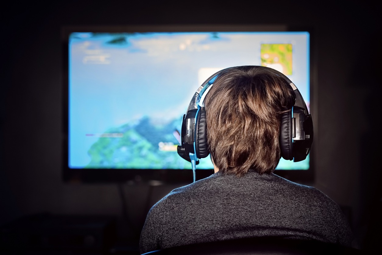 Caucasian little gamer boy wearing a headset plays video game. Video game addiction.