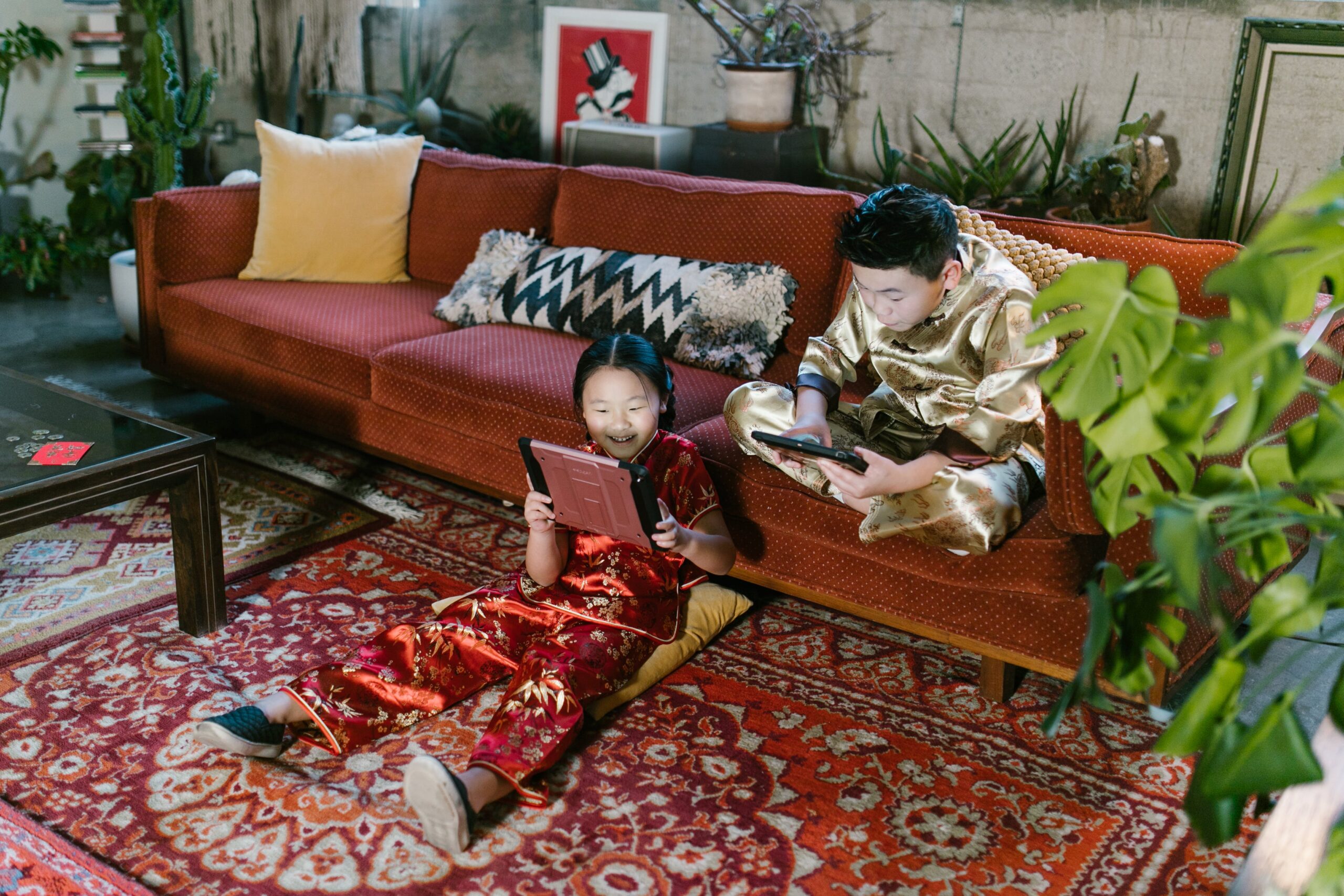 a girl and a boy sitting in the living room holding tablets